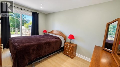 A bedroom with a bed, nightstands, and a window with a view of a fence and trees.