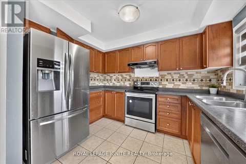 A kitchen with a stainless steel refrigerator and wooden cabinets.