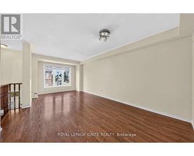 A spacious room with wooden flooring and a ceiling light fixture.