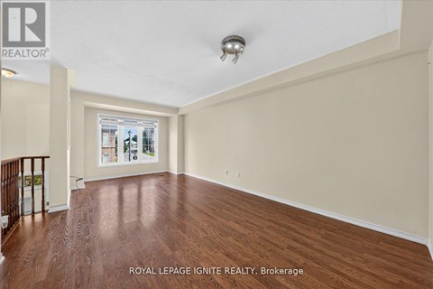A spacious room with wooden flooring and a ceiling light fixture.