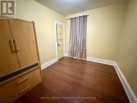 A room with a wooden floor and a brown cabinet.