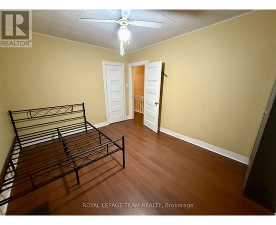 A bedroom with a bed, dresser, and ceiling fan.