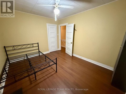 A bedroom with a bed, dresser, and ceiling fan.
