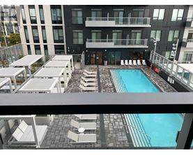 A pool area with sun loungers and a building in the background.