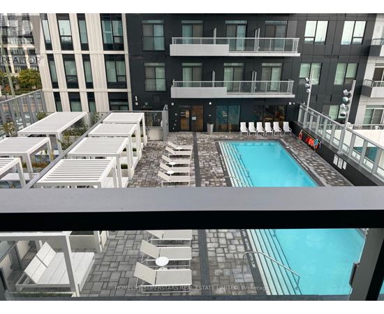 A pool area with sun loungers and a building in the background.