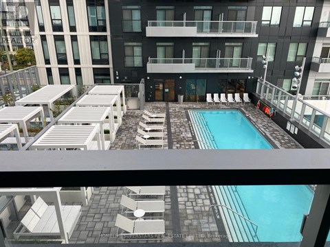 A pool area with sun loungers and a building in the background.