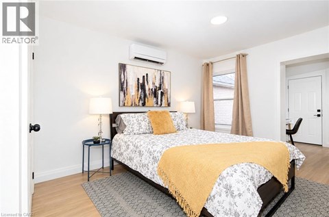 A bedroom with a bed, two lamps, and a painting on the wall.