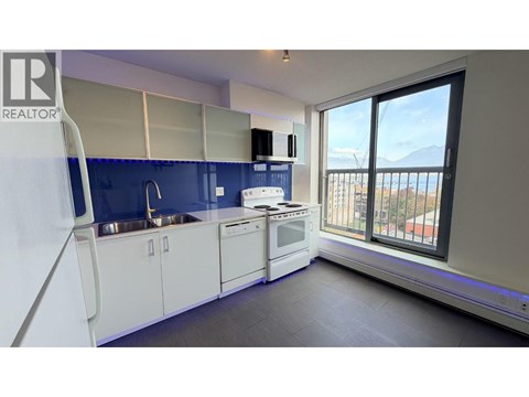 A kitchen with white cabinets and a blue backsplash.