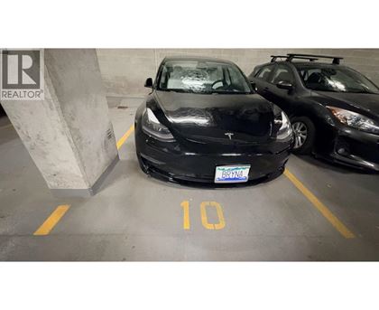 A black Tesla car is parked in a parking spot with the number 10 on the ground.
