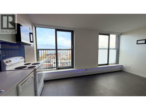 A kitchen with a stove top oven and a window overlooking a balcony.