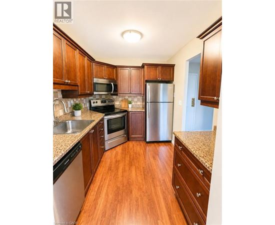 A kitchen with wooden cabinets and a stainless steel refrigerator.