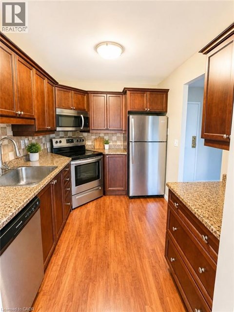 A kitchen with wooden cabinets and a stainless steel refrigerator.