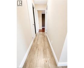 A long hallway with wood floors and white walls.
