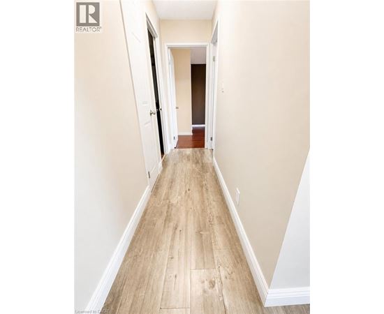 A long hallway with wood floors and white walls.