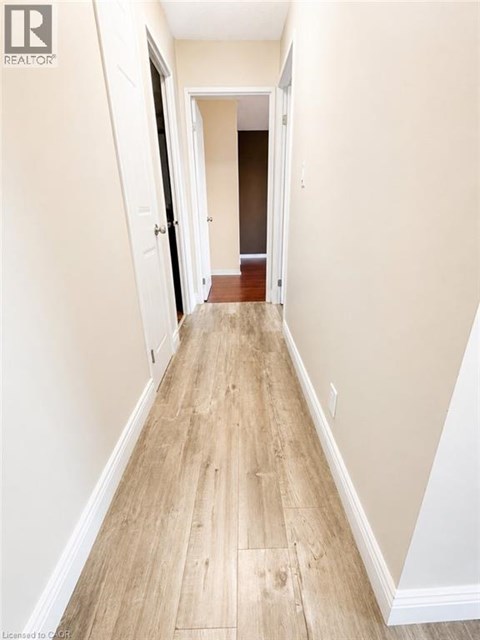 A long hallway with wood floors and white walls.