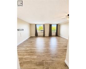 A spacious room with wooden flooring and a ceiling fan.