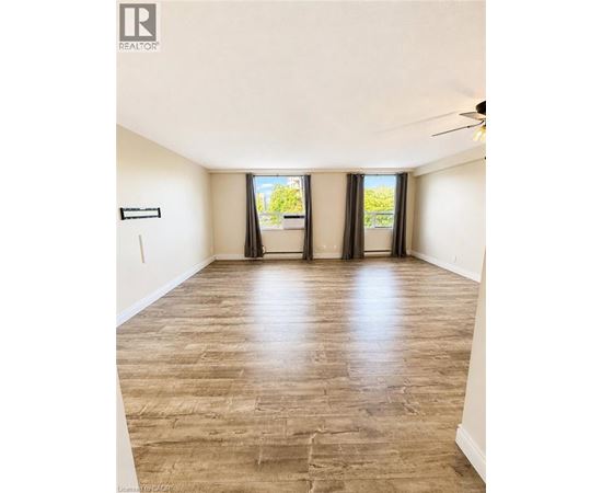 A spacious room with wooden flooring and a ceiling fan.