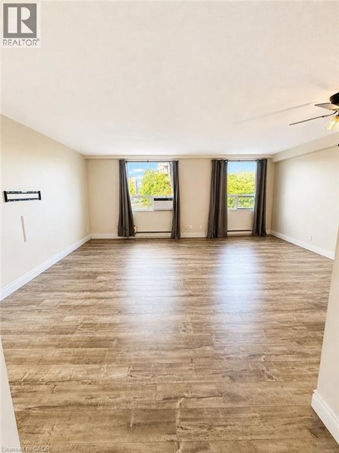 A spacious room with wooden flooring and a ceiling fan.