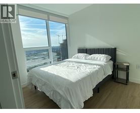 A bedroom with a large bed and a view of a construction site outside the window.
