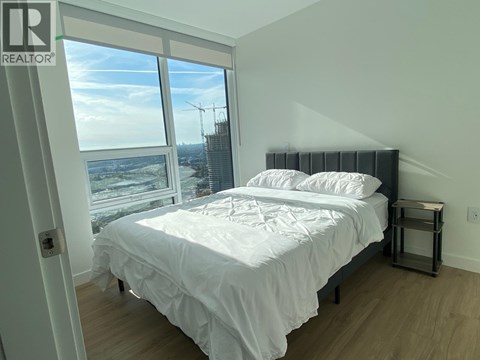 A bedroom with a large bed and a view of a construction site outside the window.