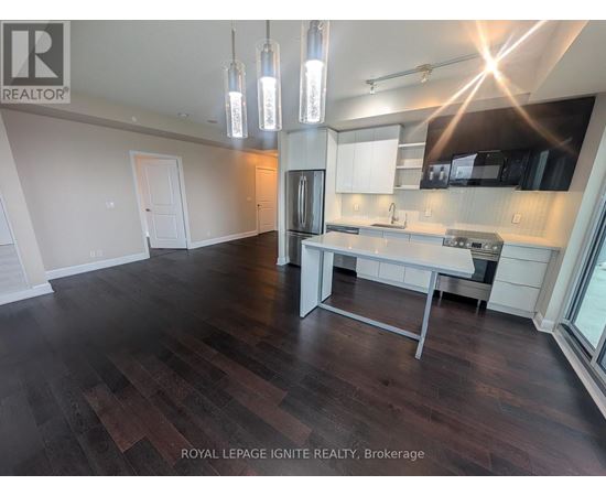 A well-lit kitchen with dark wood floors and modern appliances.
