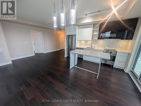 A well-lit kitchen with dark wood floors and modern appliances.