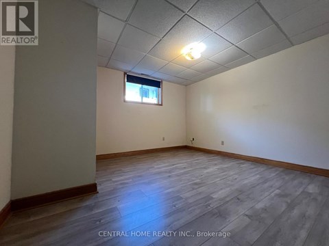 A room with wooden flooring and a window with a white frame.