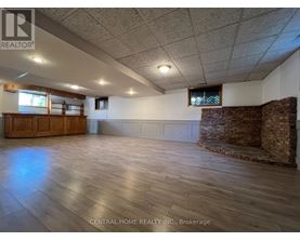 A spacious room with wooden floors and a brick wall.