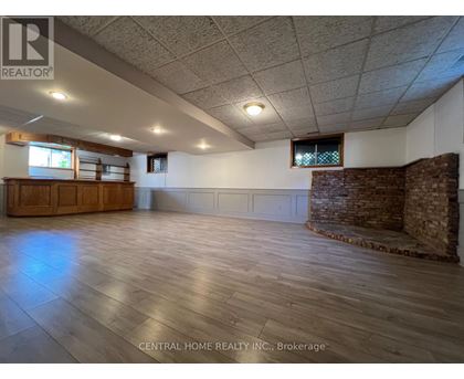 A spacious room with wooden floors and a brick wall.