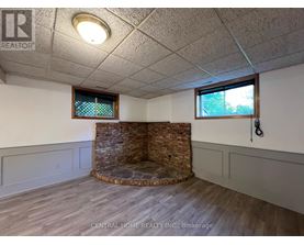 A room with a stone fireplace and wood flooring.