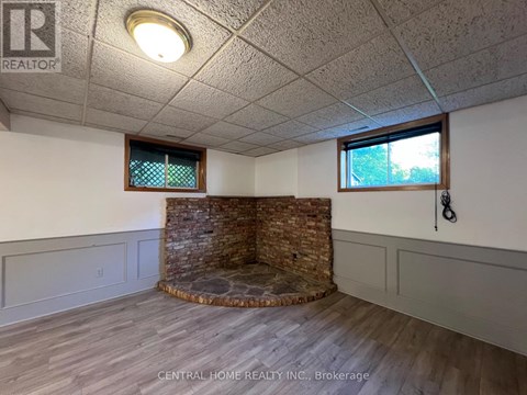 A room with a stone fireplace and wood flooring.
