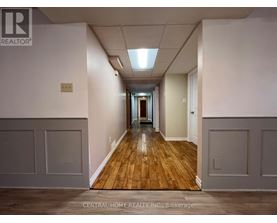 A long hallway with wood floors and white walls.