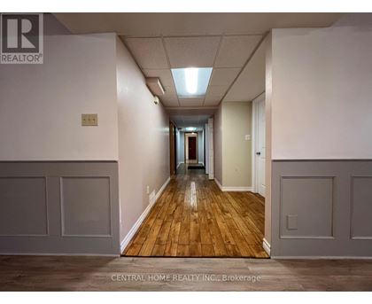 A long hallway with wood floors and white walls.