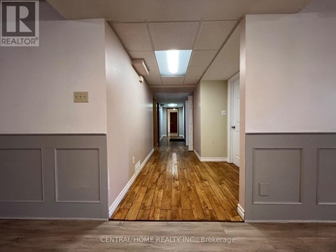 A long hallway with wood floors and white walls.