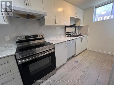 A kitchen with a black stove top oven and white cabinets.