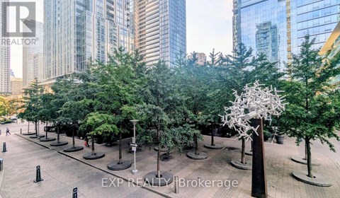 A city park with trees and a sculpture in the middle.