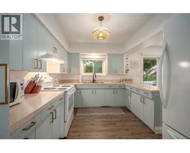 A kitchen with white cabinets and a wooden floor.