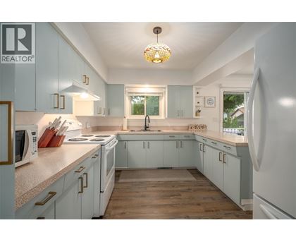 A kitchen with white cabinets and a wooden floor.