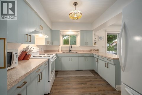 A kitchen with white cabinets and a wooden floor.