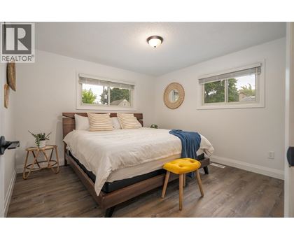 A bedroom with a bed, a stool, and a mirror on the wall.