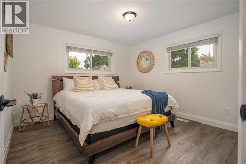 A bedroom with a bed, a stool, and a mirror on the wall.