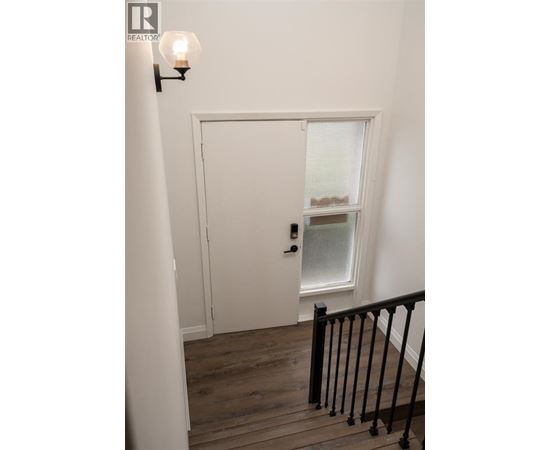 A white door with a window above it and a light on the wall.