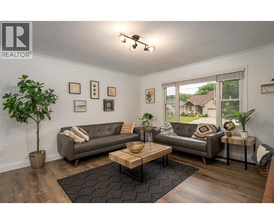 A living room with a grey couch, a coffee table, and a plant.