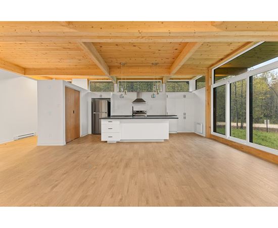 A spacious kitchen with wooden floors and a white countertop.