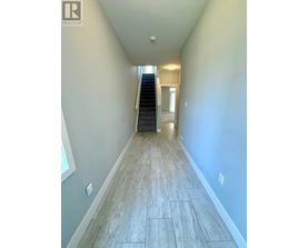 A hallway with a staircase and a door at the end.