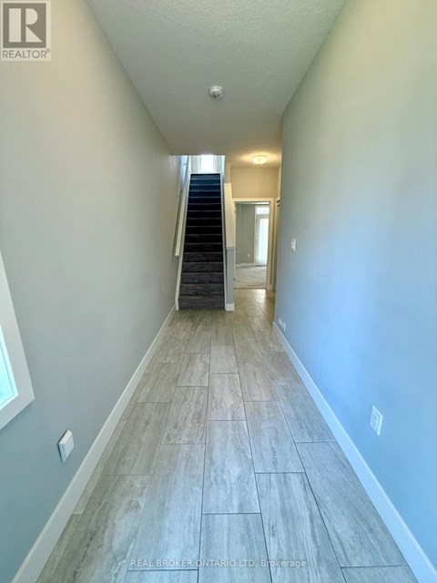 A hallway with a staircase and a door at the end.