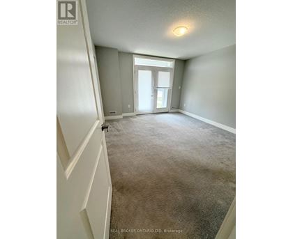 A carpeted room with a doorway leading to another room.