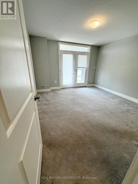 A carpeted room with a doorway leading to another room.