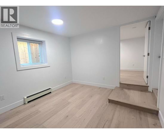 A room with wooden flooring and a window with blinds.