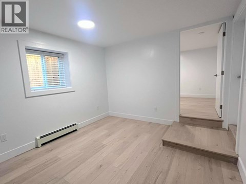 A room with wooden flooring and a window with blinds.
